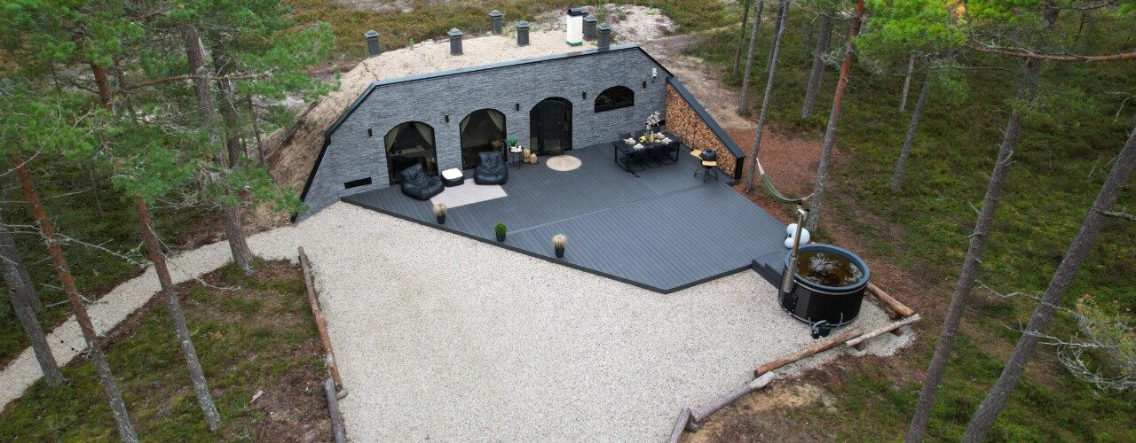 Insulated garden room with arched glazing set into a planted garden bank